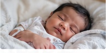 Sleeping newborn infant being monitored for healthy breathing and feeding